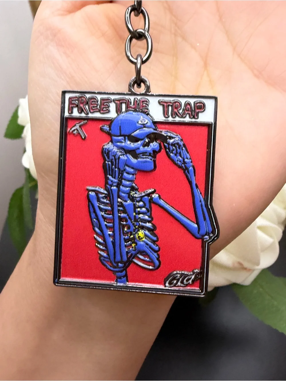 Blue Skeleton 'Free The Trap' Enamel Keychain on Red Background
